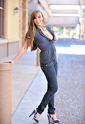 Long-haired hottie cracks a smile before pulling down her denim pants